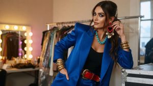 Street style look layering brooches, a scarf belt and stacked jewellery, capturing the 2026 maximalist accessorising trend