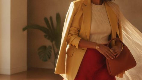 Model wearing a hammered silk midi slip skirt with a structured blazer and kitten heels, styled in the Victoria Beckham manner