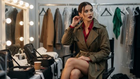 Why dressing for British weather says more about us than any trend does Woman in a beige trench coat, roll-neck jumper and scarf walking a rain-soaked London street in autumn