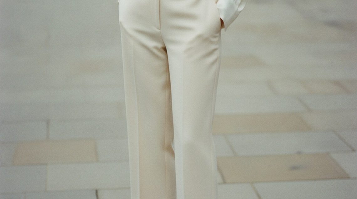 Woman wearing cream wide-leg tailored capri trousers, hemline grazing the ankle bone, sharply pressed with a clean silhouette